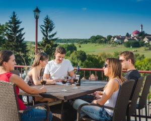 Fiatal társaság a Mokos pincészet teraszán ülve bort iszogat a napsütésben