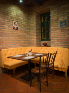 A villánykövesdi Hotel Cabernet egy asztala sárga sarokülővel, két székkel
