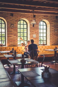 Fiatal pár az asztalnál ülve borozgatás közben vár az ételére a villánykövesdi Sárga Ház Borgerezőben