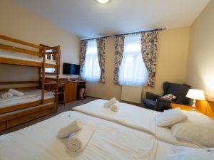A Hotel Cabernet családi emeletes ágyas szobája, a képen egy dupla ágy és egy emeletes ágy, tévé, fotel
