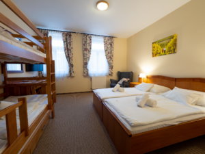 A Hotel Cabernet családi emeletes ágyas szobája, a képen egy dupla ágy és egy emeletes ágy, valamint íróasztal, fotel, tévé és tükör