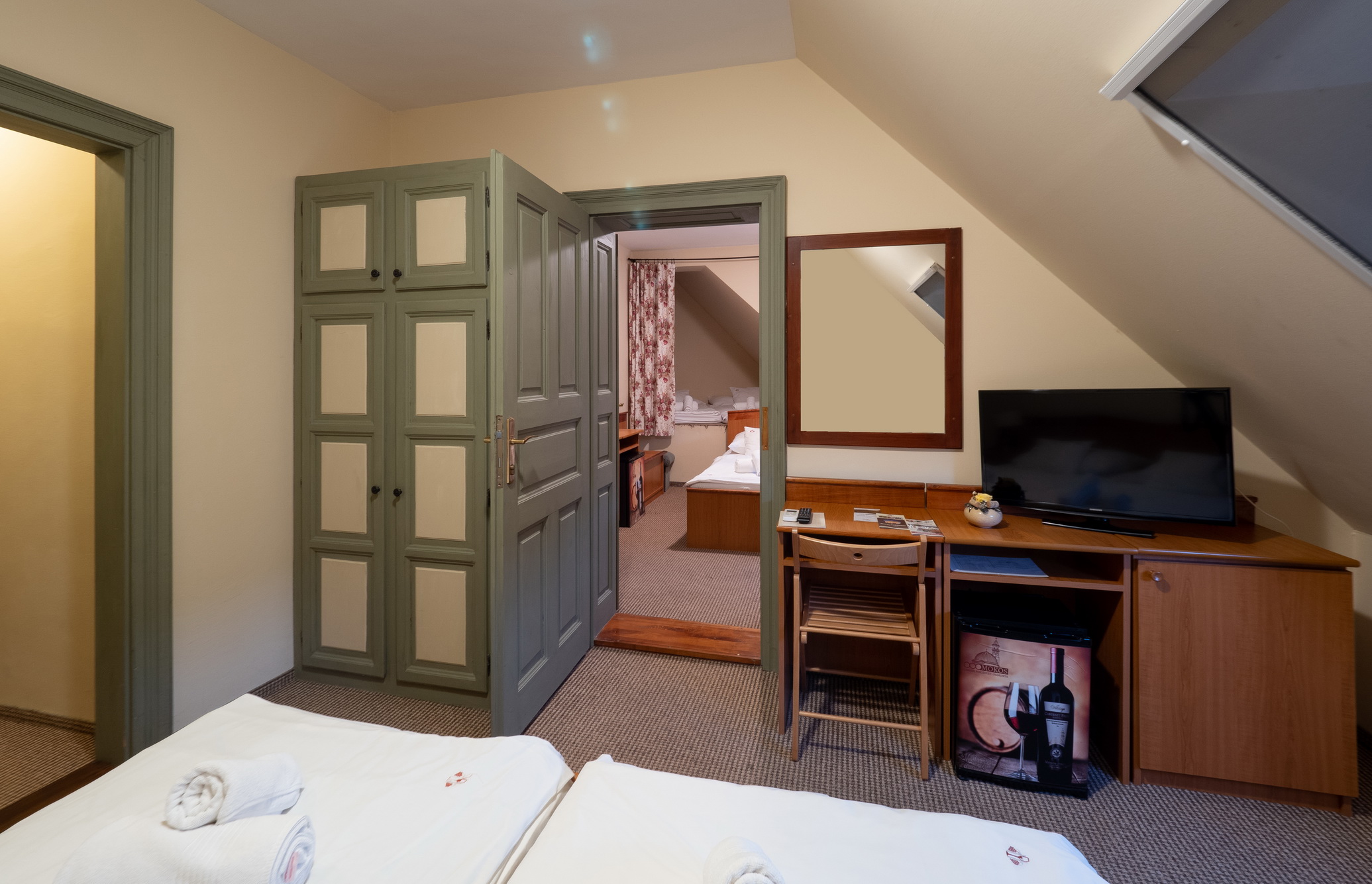 A Hotel Cabernet családi kuckós szobája, a képen egy dupla ágy és egy összenyitható plusz szoba is látható, valamint tévé, íróasztal, kis hűtő