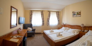 A Hotel Cabernet standard háromágyas szobája, a képen egy dupla ágy és egy külön ágy, tévé, íróasztal, fotel